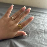 Gen 3 Gold Health Tracking Ring — gold ring worn on a hand resting on gray bedding
